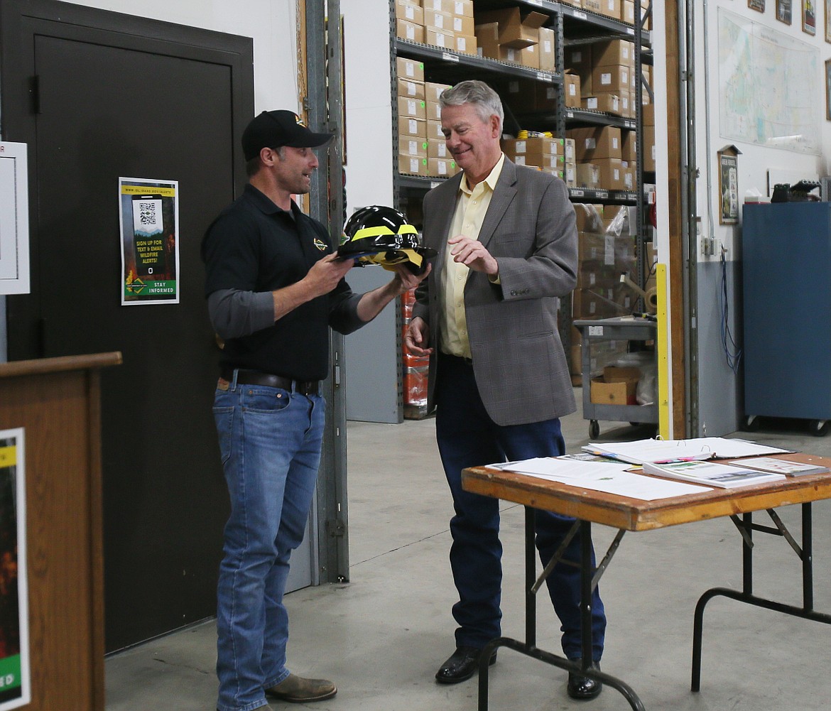 Idaho Department of Lands director Dustin Miller gifts Gov. Brad Little with his own wildland fire helmet during a tour of the Coeur d'Alene Interagency Fire Cache on Tuesday morning.