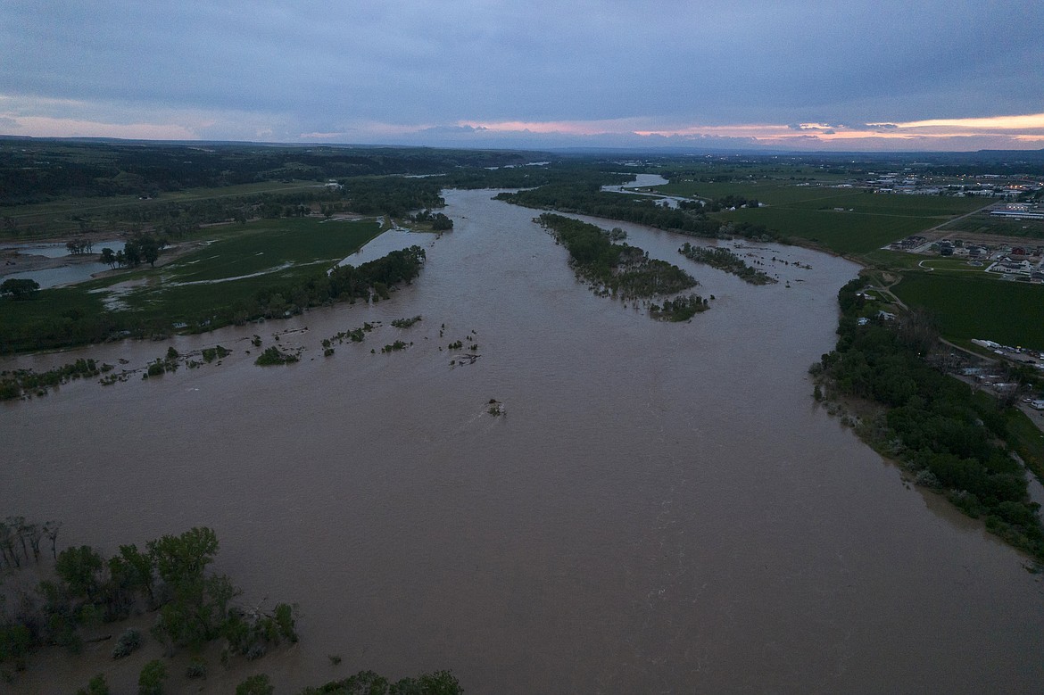 The roaring Yellowstone River is seen from the air sweeping over trees and near homes Tuesday, June 14, 2022, in Billings, Mont. (AP Photo/Brittany Peterson)