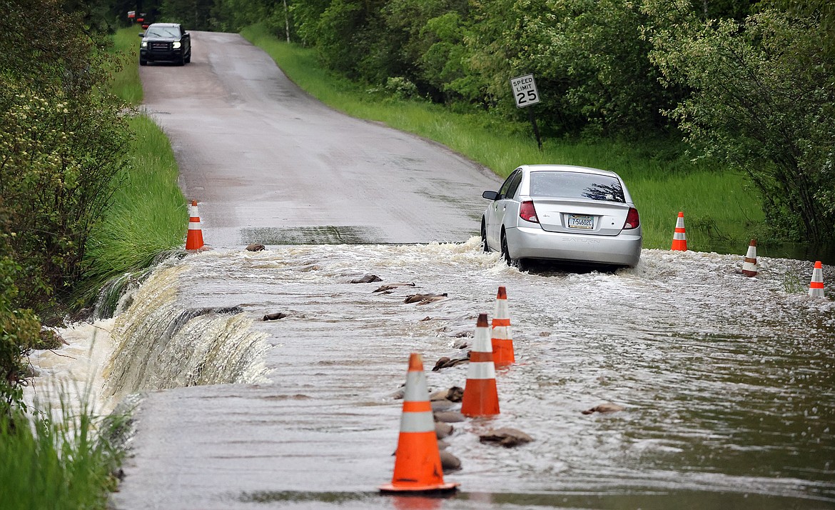 A car makes its way through the flooding along Garnier Creek on North Hilltop Road in Columbia Falls Wednesday, June 15. (Jeremy Weber/Daily Inter Lake)