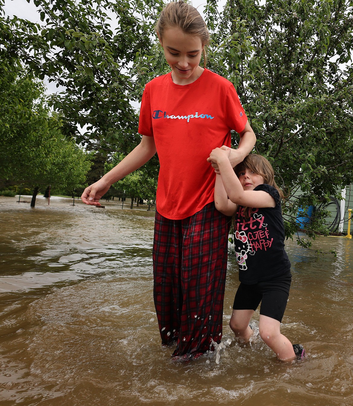 Jordan Stanley helps Ellie Henderson through the flood waters near their home in Columbia Falls Wednesday, June 15. (Jeremy Weber/Daily Inter Lake)