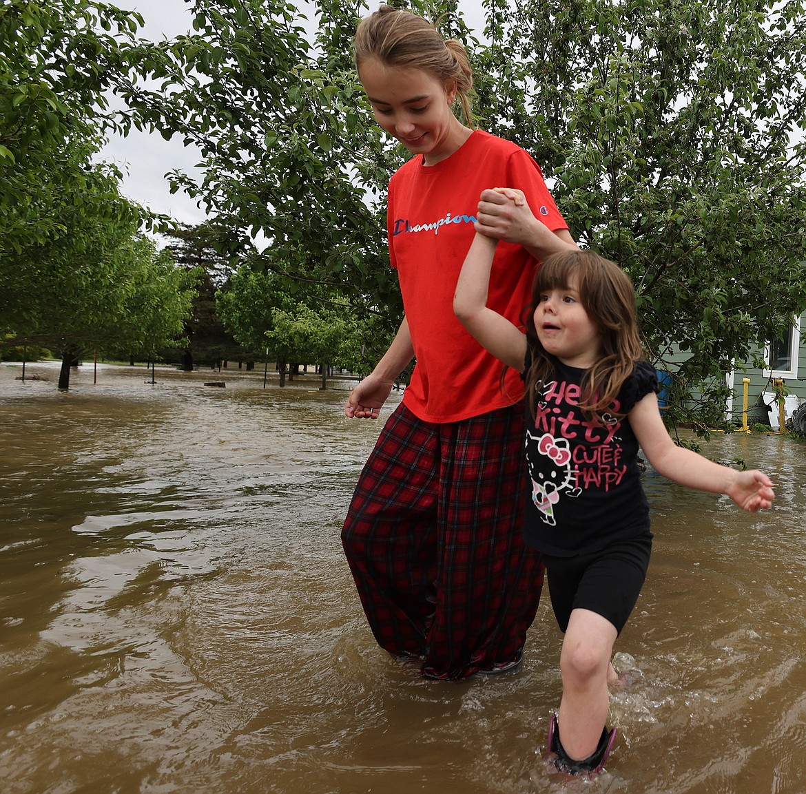 Jordan Stanley helps Ellie Henderson through the flood waters near their home in Columbia Falls Wednesday, June 15. (Jeremy Weber/Daily Inter Lake)