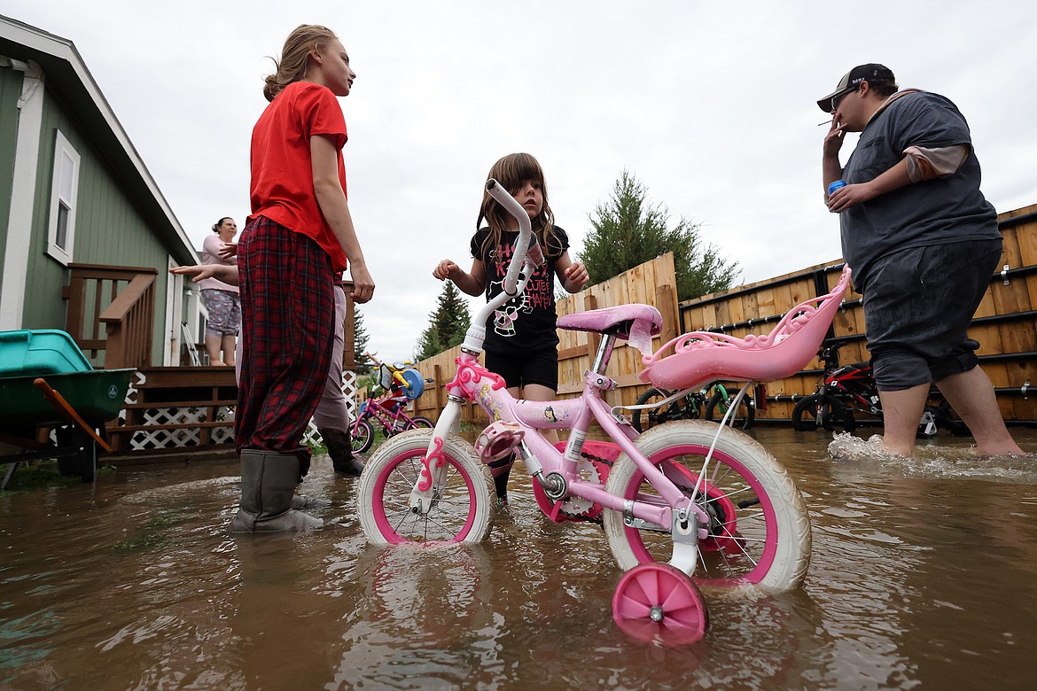 Four-year-old Ellie Henderson and her family access the flood damage outside their home in Columbia Falls Wednesday morning, June 15. (Jeremy Weber/Daily Inter Lake)