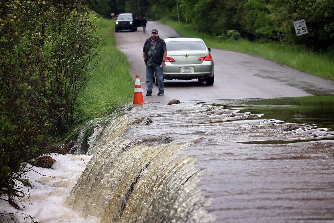 A nearby resident observes the flood waters of Garnier Creek as it flows over North Hilltop Road in Columbia Falls Wednesday, June 15. (Jeremy Weber/Daily Inter Lake)