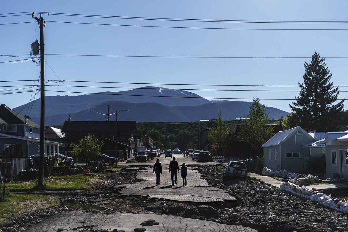 Pedestrians walk down a street washed away from Rock Creek floodwaters in Red Lodge, Mont., Wednesday, June 15, 2022. (AP Photo/David Goldman)