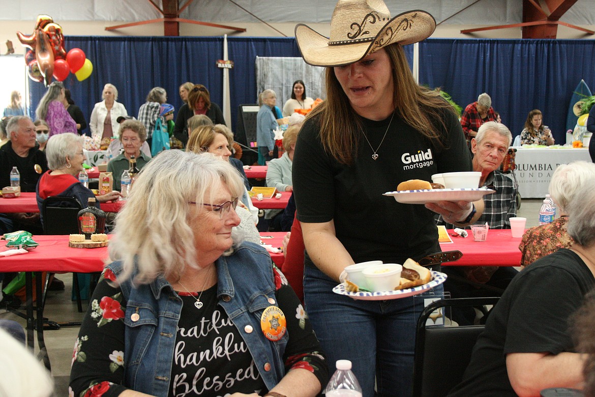 An appropriately attired volunteer serves lunch to an attendee at the Senior Picnic Wednesday at the Grant County Fairgrounds.