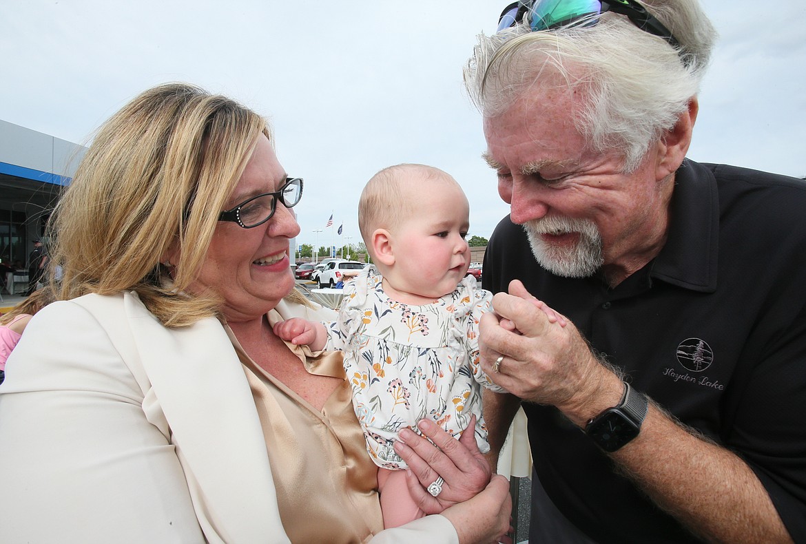 Eve Knudtsen and husband Wayne Cofield share a special moment with 7-month-old granddaughter Hazel Traw during the 83rd anniversary celebration of Knudtsen Chevrolet at the dealership in Post Falls on Thursday.