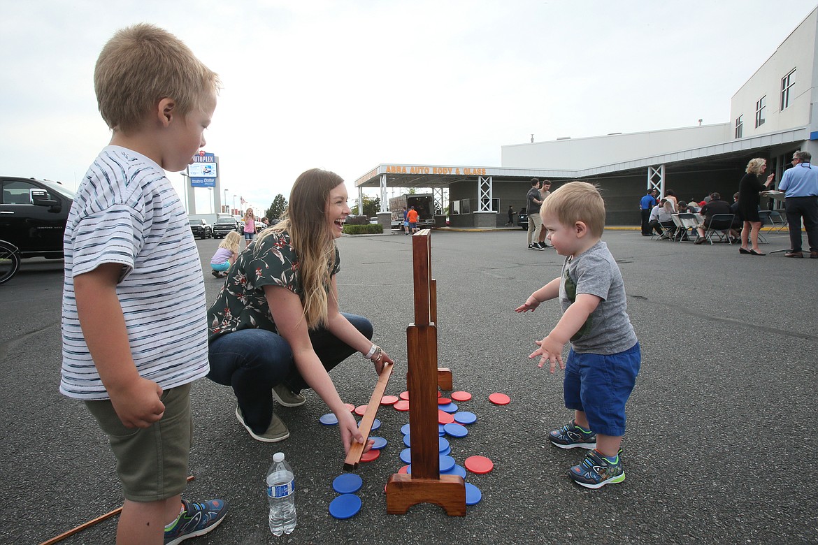 Mom Sam Layson, 4-year-old Elliott, left, and 1-year-old Jackson play Connect Four during the 83rd anniversary party Thursday at Knudtsen Chevrolet in Post Falls.