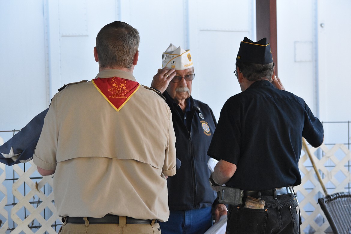 First Vice-Commander Larry McCarty salutes back to Sergeant-at-Arms Ken Koplin as Koplin presents the flags to be retired for inspection with Boy Scout Richard Roloff.