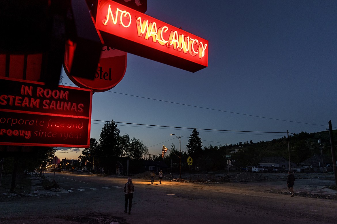 Pedestrians pass a motel in Red Lodge, Mont., while surveying the damage after floodwaters receded, Wednesday, June 15, 2022. On Wednesday, residents in Red Lodge, a gateway town to Yellowstone National Park's northern end, used shovels, wheelbarrows and a pump to clear thick mud and debris from flooded homes along the banks of Rock Creek. (AP Photo/David Goldman)