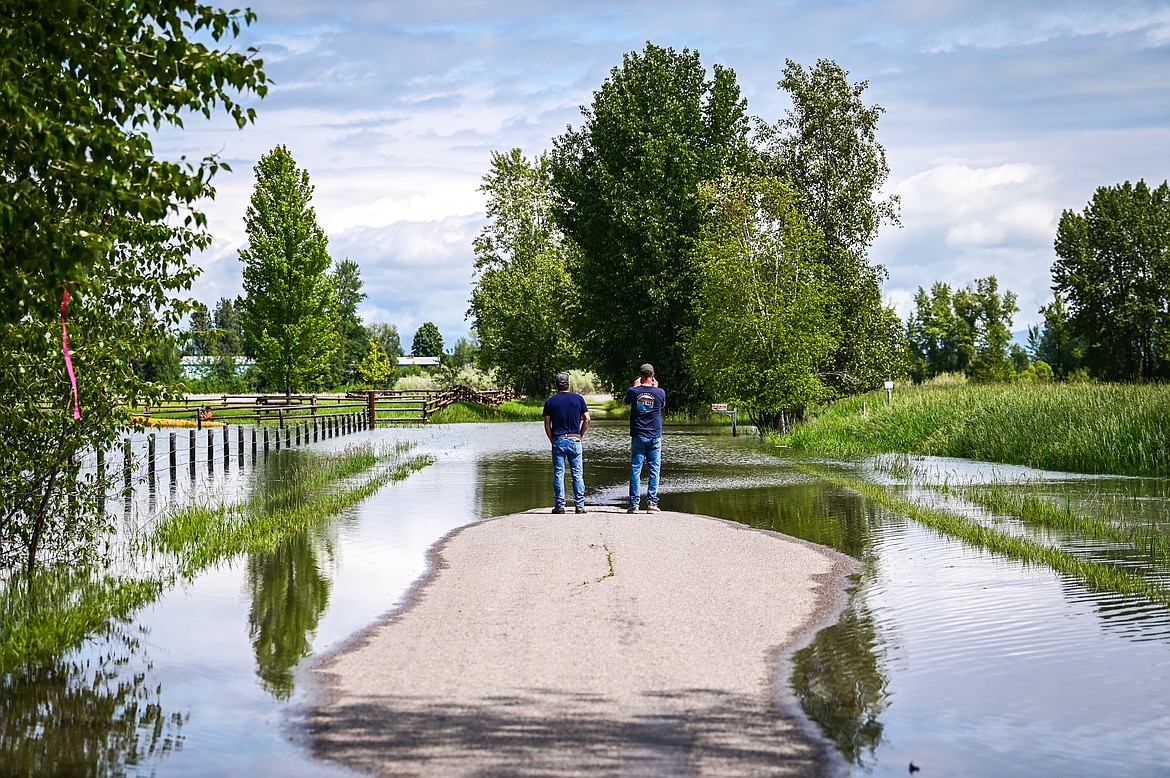 Dave Johnston and Ken Jarvis take photographs of the flooding along Wagner Lane on Tuesday, June 21. (Casey Kreider/Daily Inter Lake)