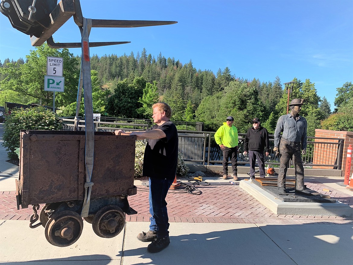 Bud Brisson helps guide the ore cart toward its new home next to The Miner on Wednesday.