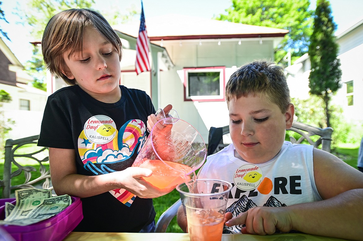 Ember Reed and Jaxon Bertrands pour a cup of strawberry lemonade at their Lemonade Blast stand as part of Lemonade Day in Kalispell on Saturday, June 25. The national Lemonade Day program helps youth learn about starting a business, via the one-day stands. Through guided lessons in their Lemonade Day booklet, they learn about budgeting, finance, site selection, product creation, supplies, staffing, and more. (Casey Kreider/Daily Inter Lake)