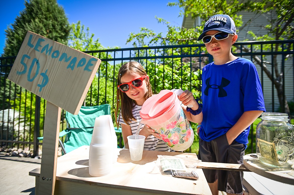 Noelle and Vincent Greel serve up a cup of their lemonade at their Cup of Sunshine stand as part of Lemonade Day in Kalispell on Saturday, June 25. The national Lemonade Day program helps youth learn about starting a business, via the one-day stands. Through guided lessons in their Lemonade Day booklet, they learn about budgeting, finance, site selection, product creation, supplies, staffing, and more. (Casey Kreider/Daily Inter Lake)
