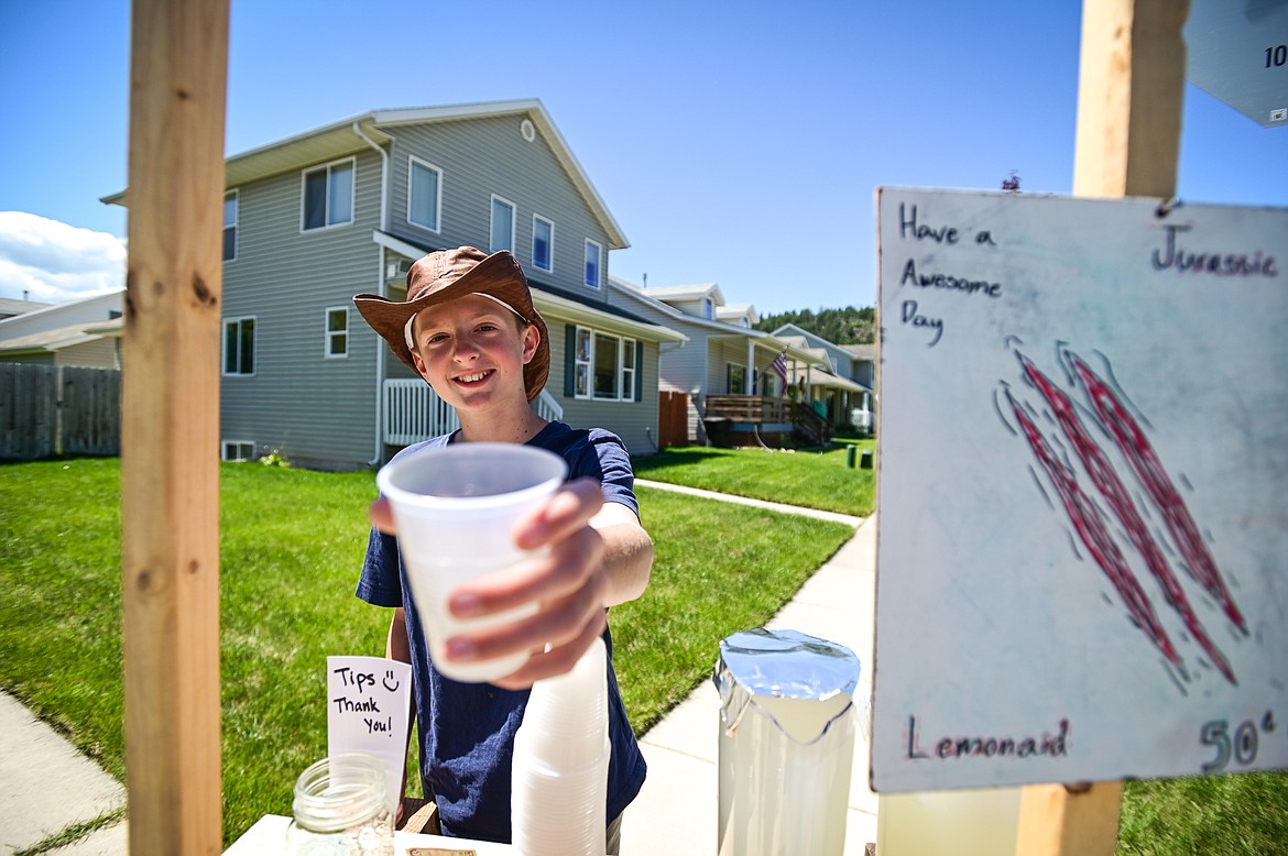Greyson Greel serves up a cup of lemonade at his Jurassic Lemonaid stand as part of Lemonade Day in Kalispell on Saturday, June 25. The national Lemonade Day program helps youth learn about starting a business, via the one-day stands. Through guided lessons in their Lemonade Day booklet, they learn about budgeting, finance, site selection, product creation, supplies, staffing, and more. (Casey Kreider/Daily Inter Lake)