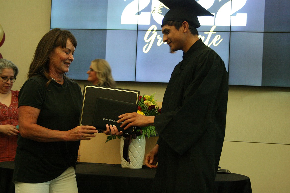 An Open Doors graduate (right) accepts his diploma from Moses Lake School Board member Shannon Hintz during the ceremony.