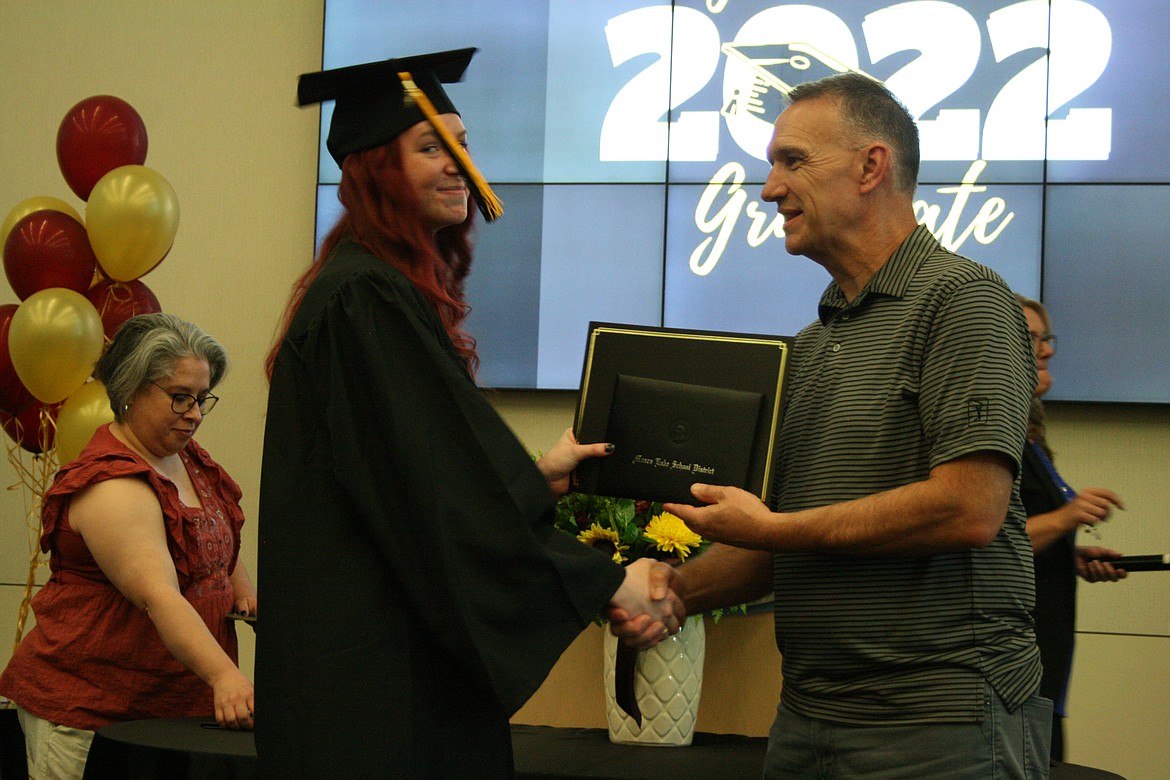 An Open Doors graduate (right) is congratulated by Moses Lake School District board member Kevin Fuhr.