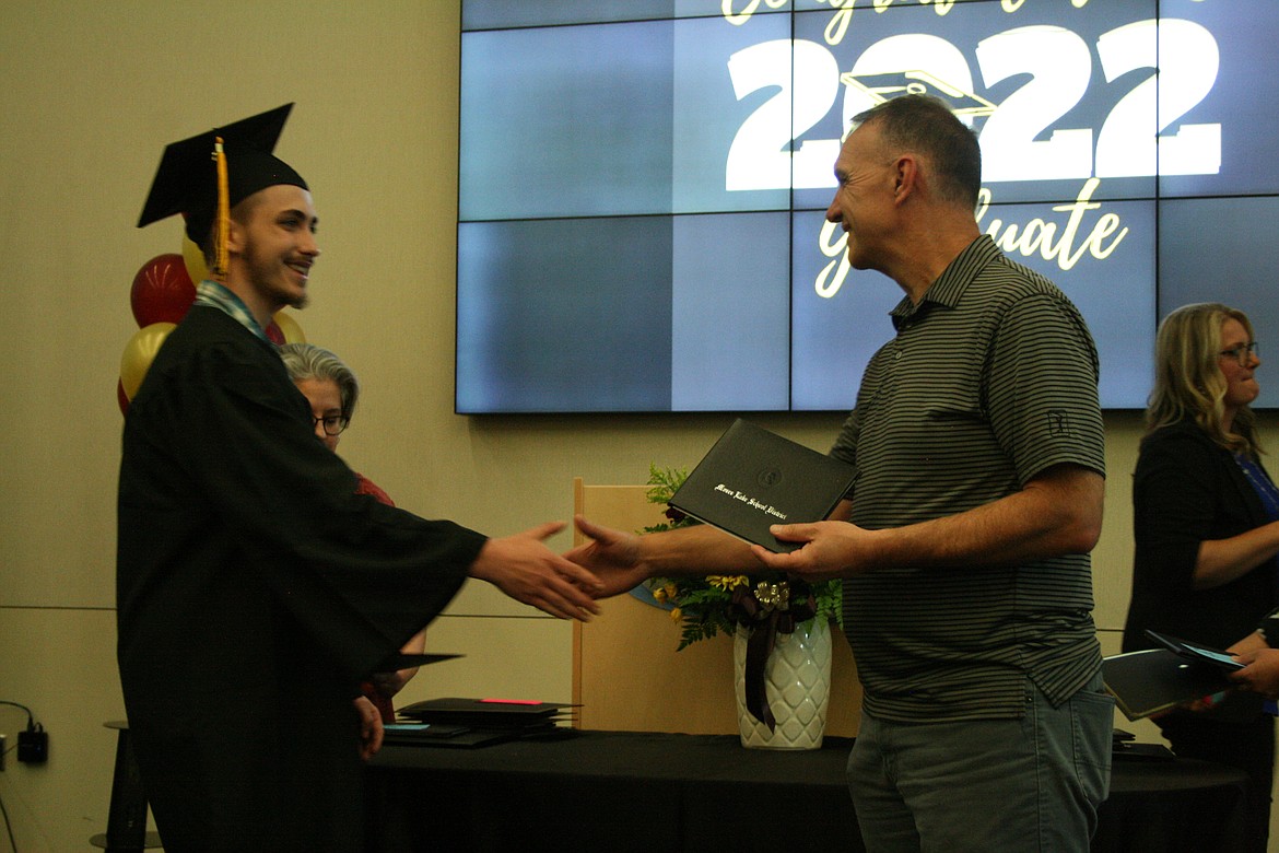 Graduation from the Open Doors program represented a milestone for many of its participants, according to some of the graduates.  A graduate (left) accepts his diploma from Moses Lake School Board President Kevin Fuhr.