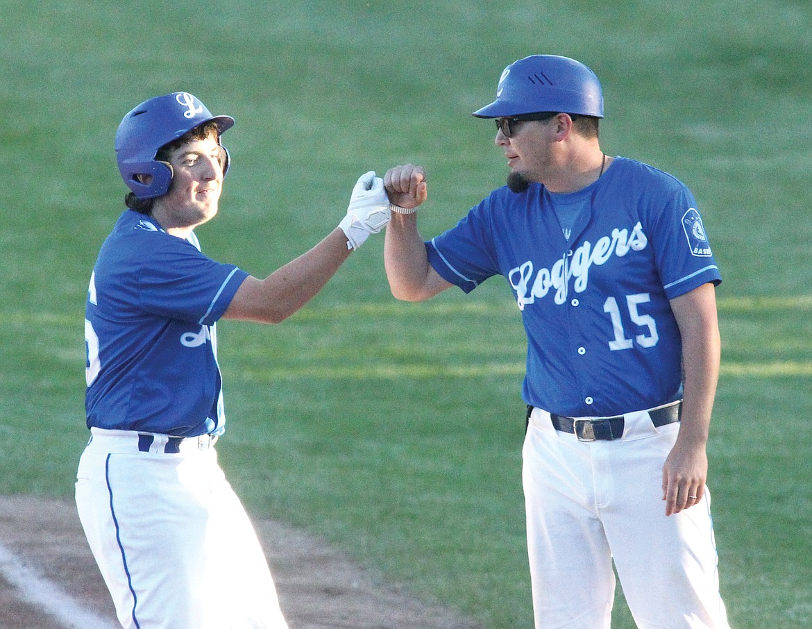 Chase Rayome exchanges "knucks" with first base coach Joe Flores following his RBI base hit scoring Caleb Moeller in the bottom of third inning. Rayome's single helped the Loggers to a 6-4 win over Latah, Idaho, last Friday evening. (Paul Sievers/The Western News)