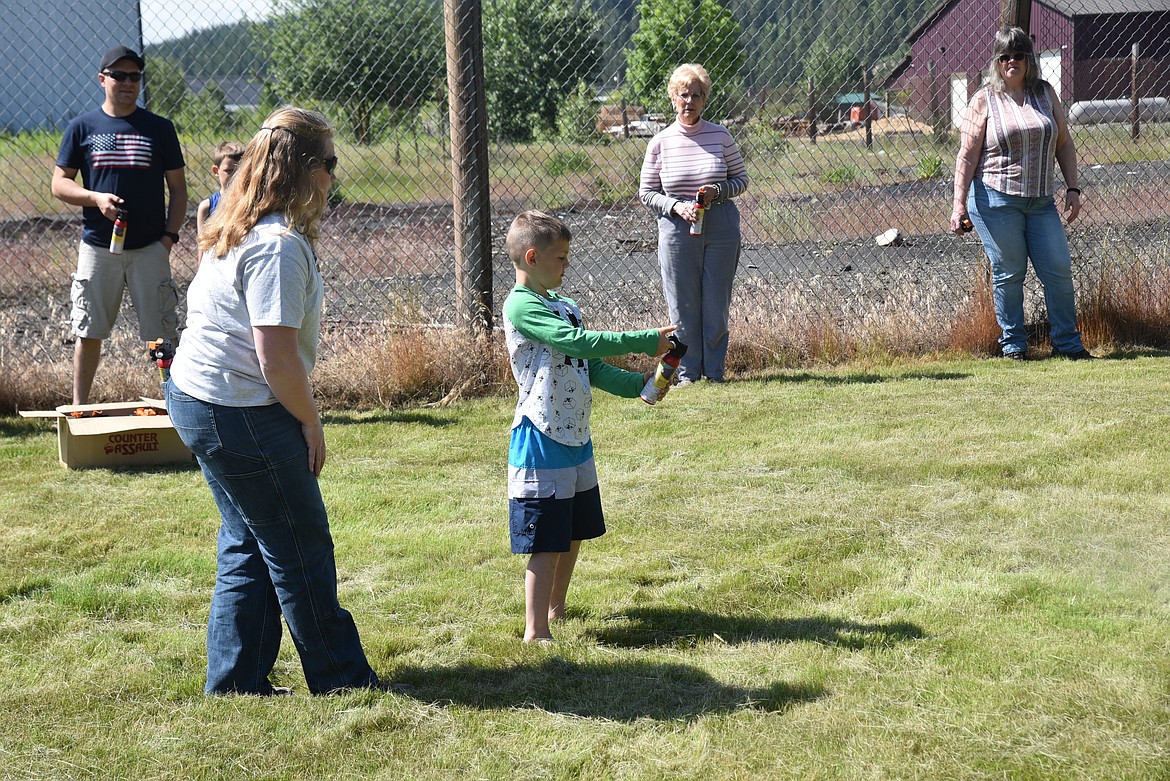 Montana Fish, Wildlife and Parks bear technician Liz Templin instructs Kevin Reeves how to fire an inert bear deterrent canister during a June 18 presentation about living and recreating in bear country. (Scott Shindledecker/The Western News)