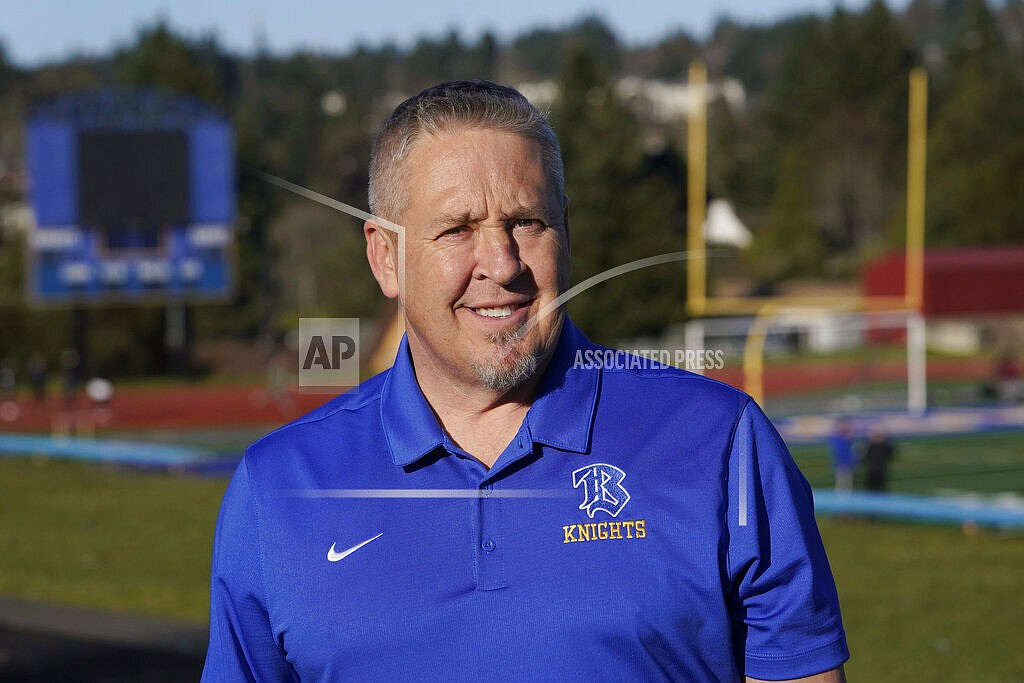 Joe Kennedy, a former assistant football coach at Bremerton High School in Bremerton, Wash., poses for a photo March 9, 2022, at the school's football field. The Supreme Court has sided with a football coach from Washington state who sought to kneel and pray on the field after games. The court ruled 6-3 along ideological lines for the coach. The justices said Monday the coach's prayer was protected by the First Amendment. (AP Photo/Ted S. Warren, File)