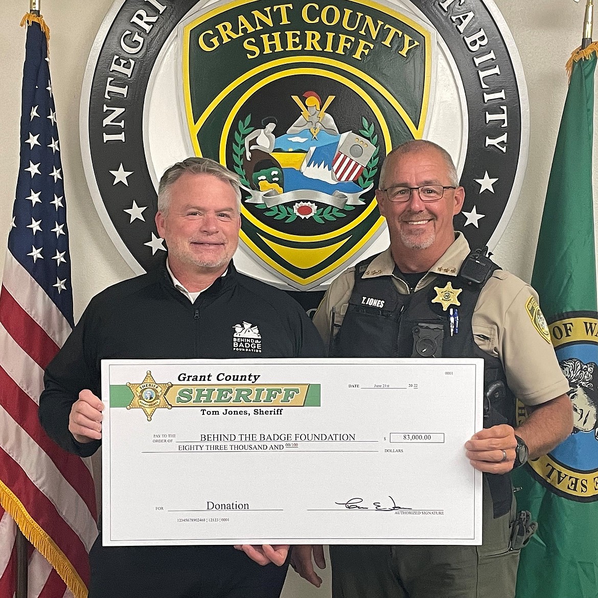 Grant County Sheriff Tom Jones, right, presents a check for $83,000 to Behind the Badge Foundation Executive Director Brian Johnston, left, on Monday.