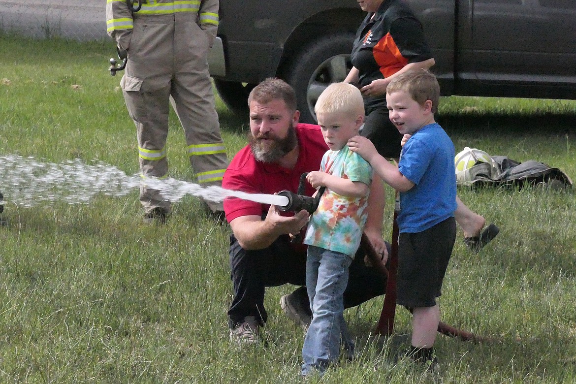 Plains Fire Chief Anthony Young helps 5-year-olds Stetson and Garrett as they shoot water toward a wooden target during a fire safety presentation this past week for K-4 students at Plains School. (Chuck Bandel/VP-MI)