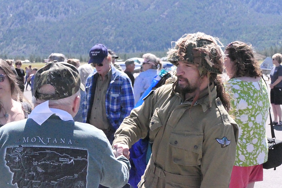 Missoula smokejumper Jonathon Fuentes shakes hands with a veteran after landing safely following a jump display Saturday at the Thompson Falls Airport. (Chuck Bandel/VP-MI)