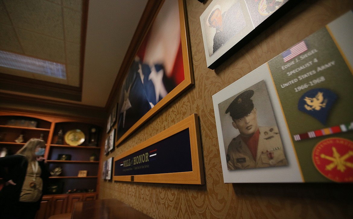 Garden Plaza of Post Falls sales associate Jessie Stevenson, back left, reads some of the displays on the Wall of Honor in the assisted living side of Garden Plaza on Tuesday.