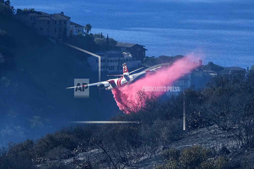 A plane drops retardant on a wildfire near homes Thursday, Feb. 10, 2022, in Laguna Beach, Calif. U.S. officials are testing a new wildfire retardant after two decades of buying millions of gallons annually from one supplier, but watchdogs say the expensive strategy is overly fixated on aerial attacks at the expense of hiring more fire-line digging ground crews. (AP Photo/Ringo H.W. Chiu, File)