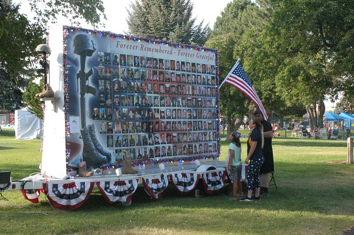 Kris Hemmerling, right, talks with Cassandra Sallis and her daughter Joy Sallis about the Time of Remembrance wall of photos. Each photo is of a northwesterner who gave their life for their country in the U.S. military.