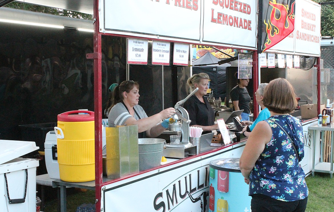 Cynthia Small, left, owner of Smulligans Pizza & BBQ in Moses Lake, squeezes lemons for lemonade while Kris St. George helps a customer.
