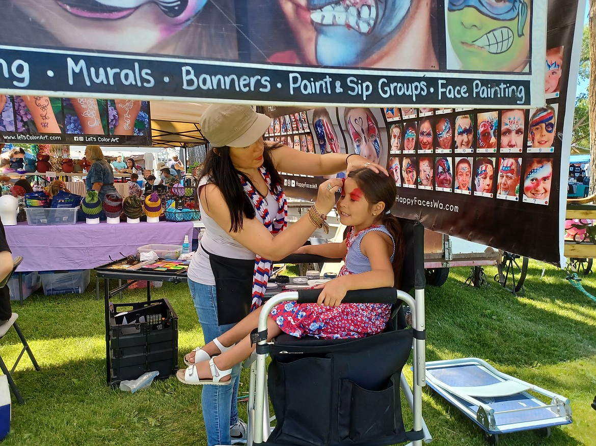 Kathy Hirschel gusses up 5-year-old Camila Ramirez at the George Independence Day celebration Monday. Face painting was one of several family-friendly activities at the event.