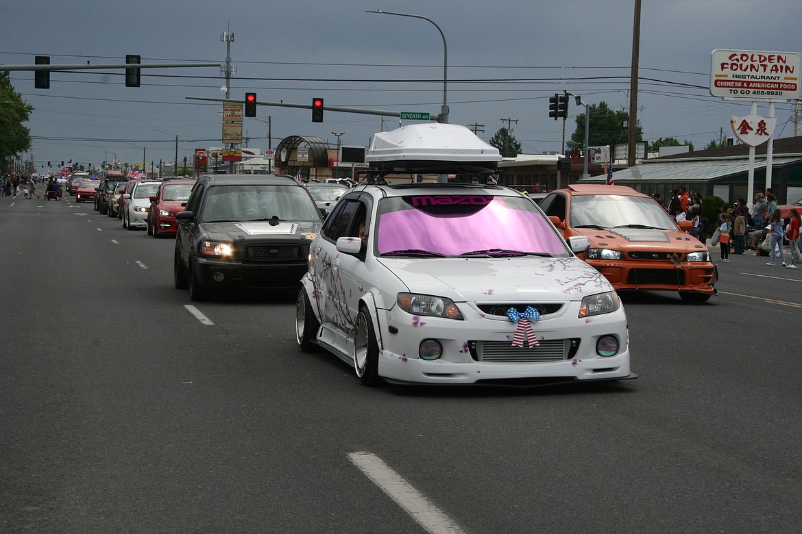 A pink and white Mazda leads a contingent of cars down the parade route in Othello July 4.