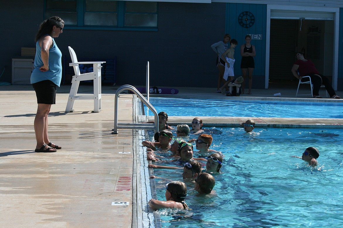 Quincy swim team members line up along the edge of the pool to listen to volunteer coach Karen Escure.