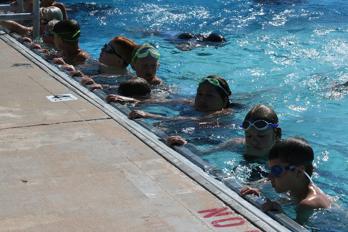 Quincy swim team members line up for instruction, and show they’re paying attention, according to the coach, by having both hands on the edge of the pool.