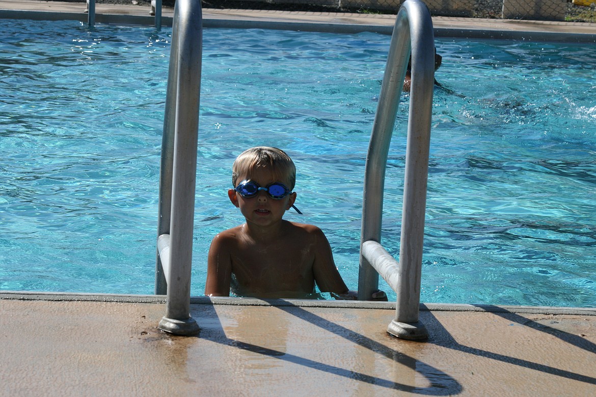 A Quincy swim team participant takes a rest on the pool ladder.