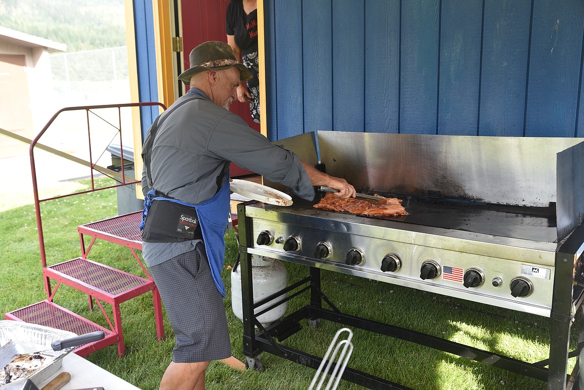 Knights of Columbus member Darryl Pfeifer puts chicken on the grill on Monday at Roosevelt park during Troy's Old Fashioned Fourth of July parade. (Scott Shindledecker/The Western News)