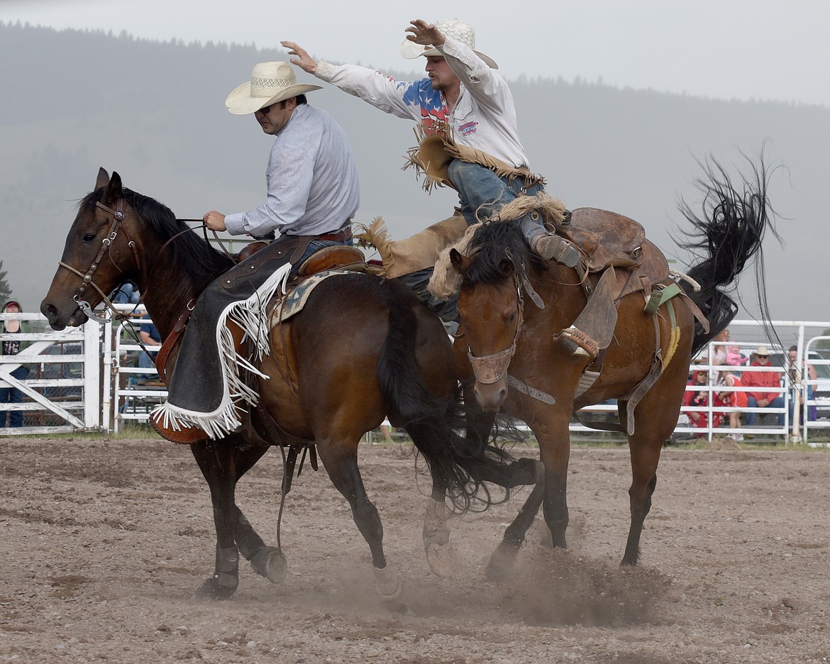 After a high scoring ride Dusty Morigeau launches from his bronc to the safety of the pickup rider's mount. (Marla Hall/For the Leader)