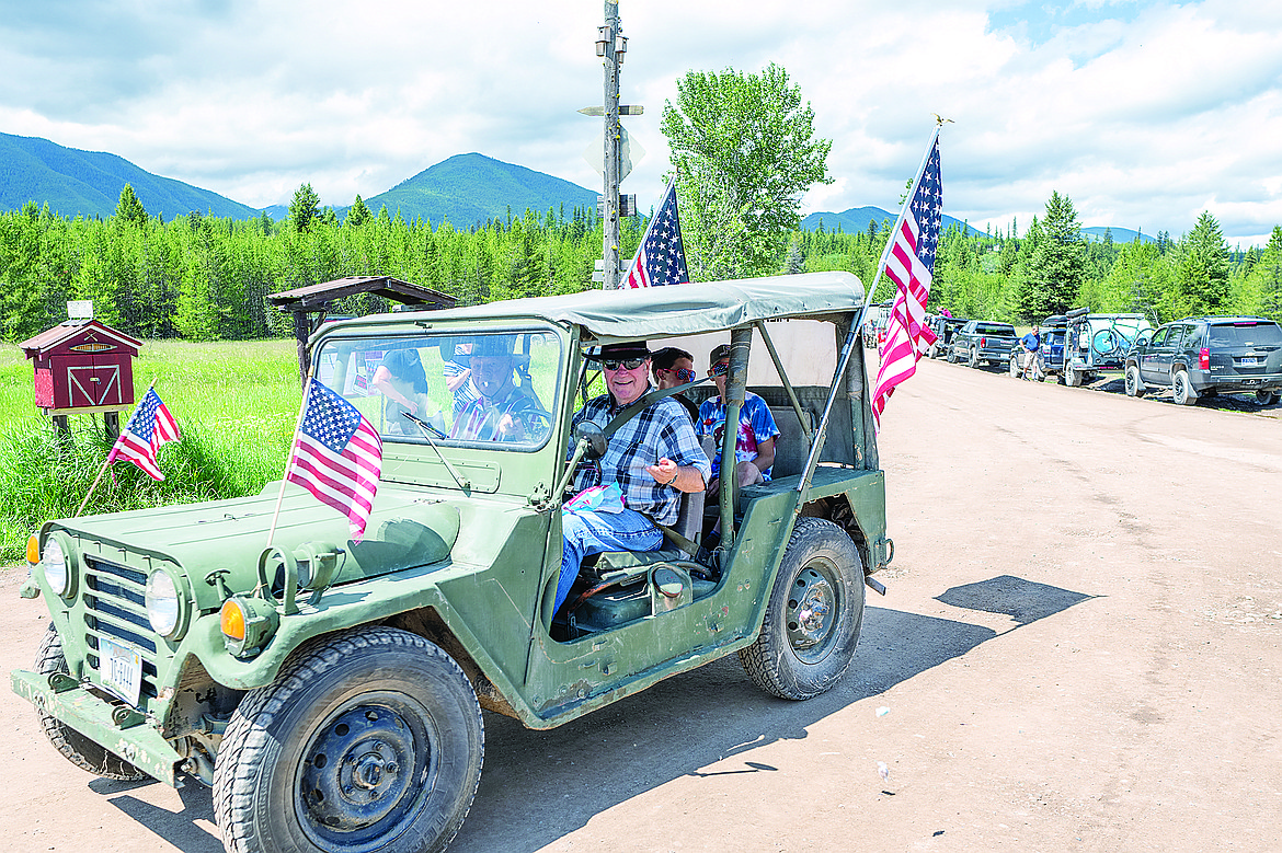 A Jeep adorned in flags floats through the parade.