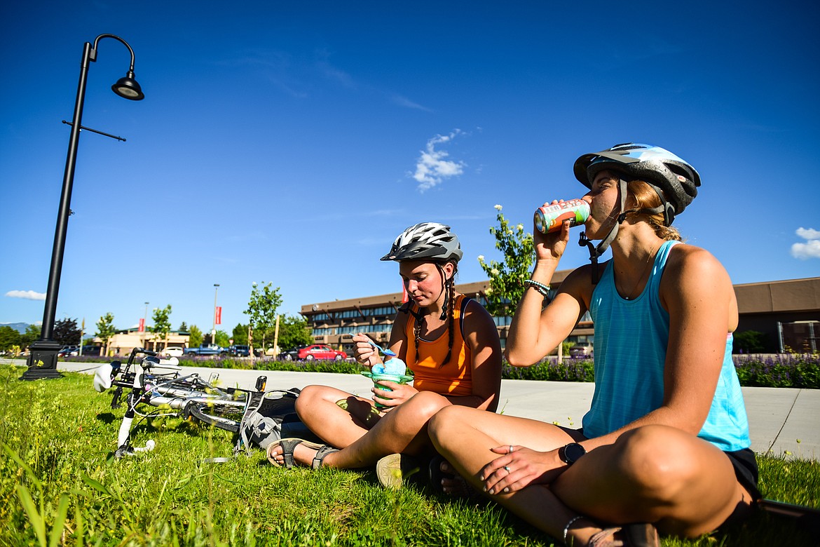 Siera Dilworth and Tess Huckeba enjoy a Glacier Shave Ice and a cold beverage as they take a break from riding bikes along the Parkline Trail in Kalispell on Tuesday, July 5. (Casey Kreider/Daily Inter Lake)