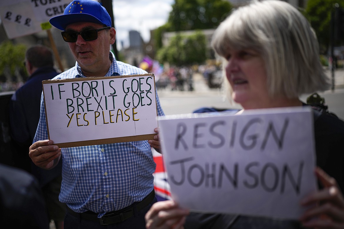 People holds placards as they protest outside the Houses of Parliament, in London, Wednesday, July 6, 2022. A defiant British Prime Minister Boris Johnson is battling to stay in power after his government was rocked by the resignation of two top ministers. His first challenge is getting through Wednesday, where he faces tough questions at the weekly Prime Minister's Questions session in Parliament, and a long-scheduled grilling by a committee of senior lawmakers. (AP Photo/Matt Dunham)