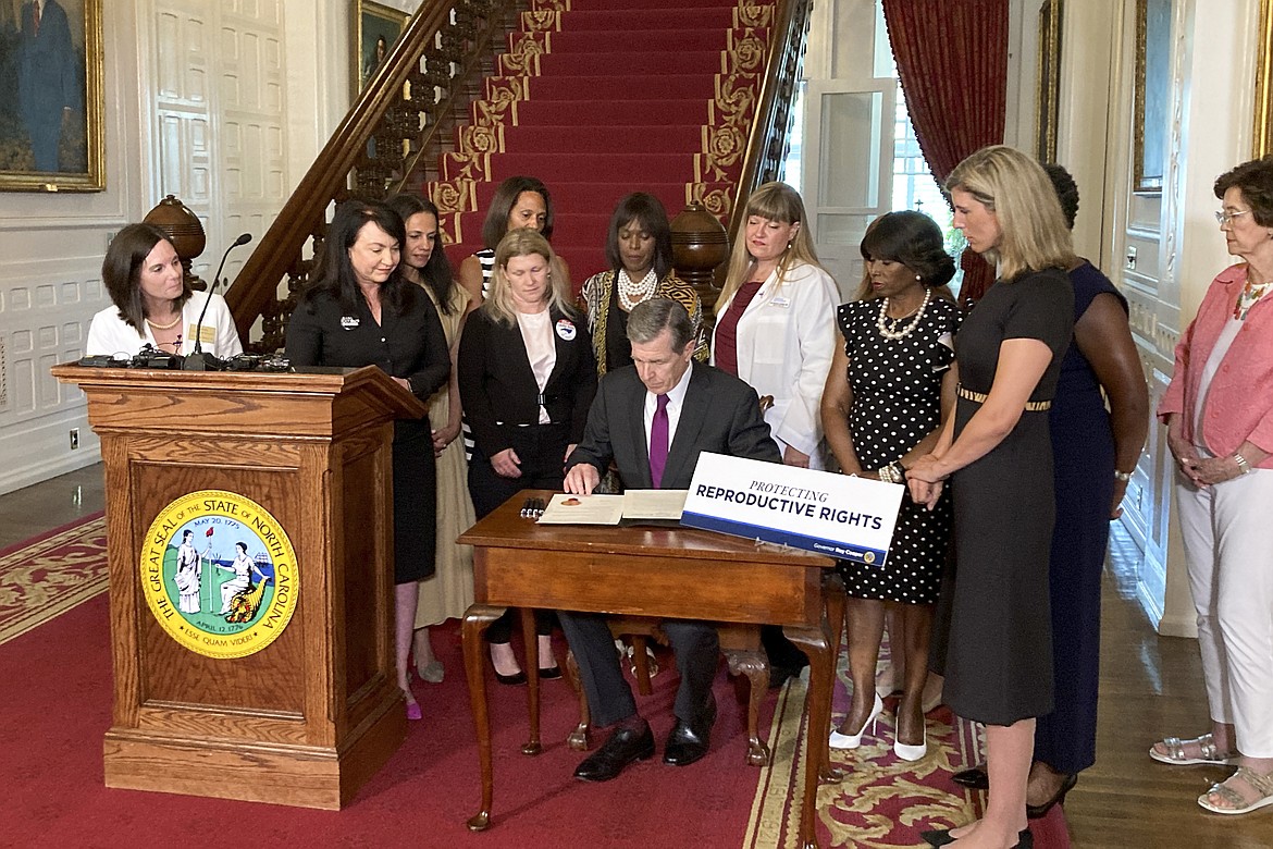 North Carolina Democratic Gov. Roy Cooper signs an executive order designed to protect abortion rights in the state at the Executive Mansion in Raleigh, N.C. on Wednesday, July 6, 2022. The order in part prevents the extradition of a woman who receives an abortion in North Carolina but may live in another state where the procedure is barred. (AP Photo/Gary D. Roberts)