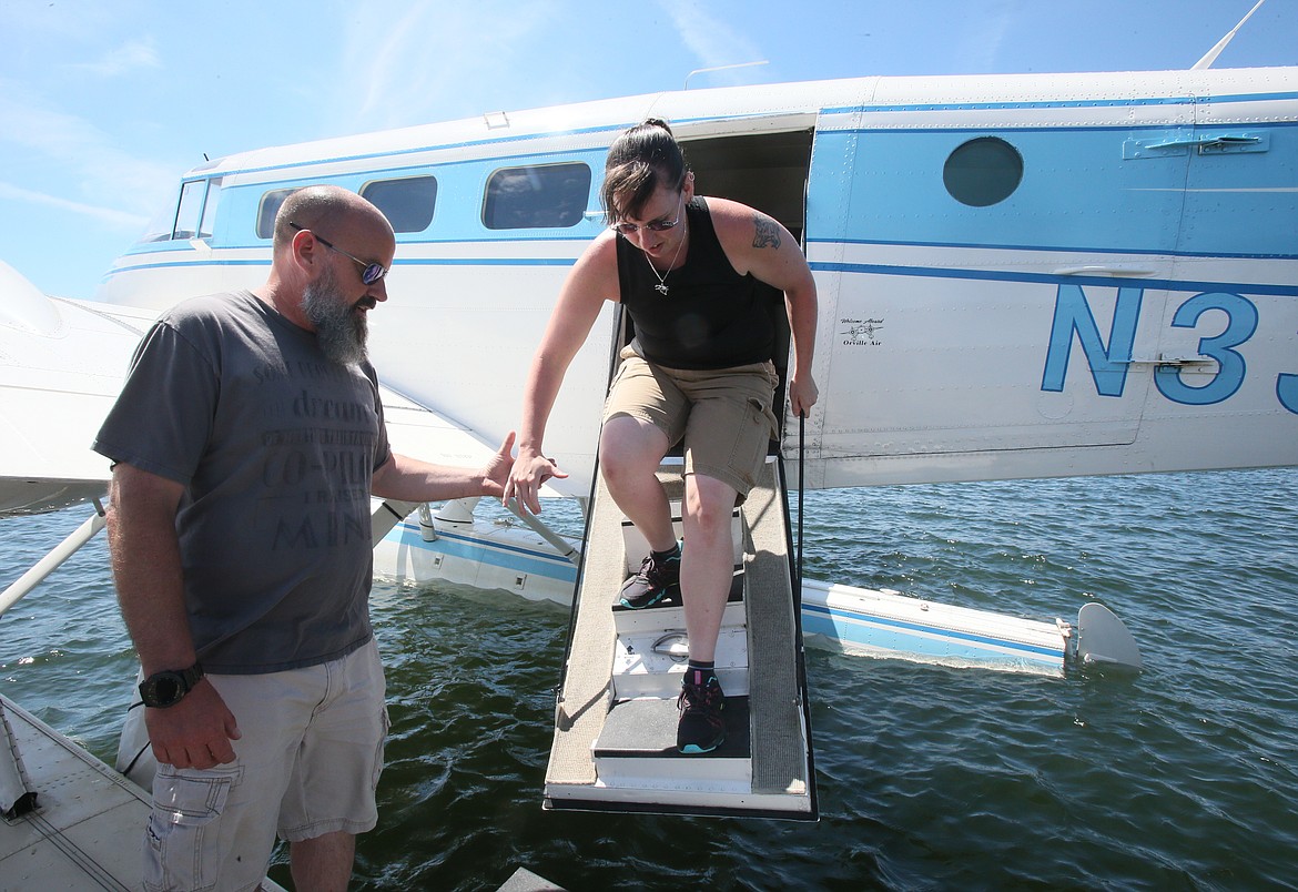 Brooke's Seaplane owner Shane Rogers helps visitor Lia Smazik out of a 1954 Beech 18 seaplane at the Independence Point dock Wednesday.