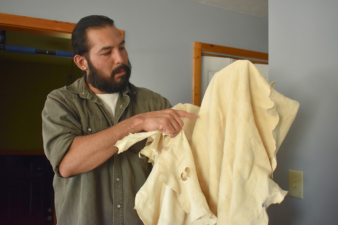 Hide tanner Kenneth Cook holds up deer hides he “brain-tanned.” Cook explains that leather made using this traditional technique is more durable and strong enough to stand up to traditional stitch work compared with commercially tanned leather. (Aaron Bolton for KHN)