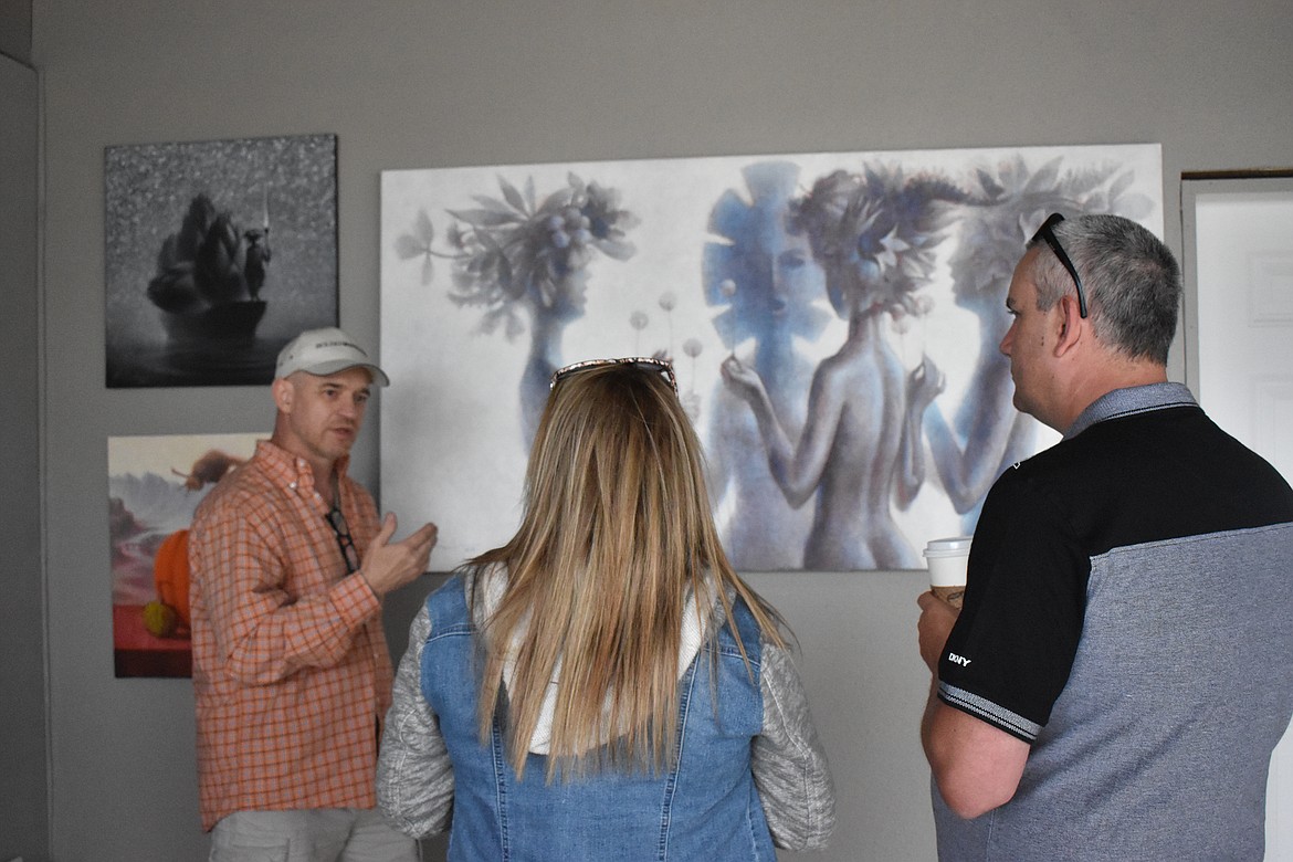 The artist, Mihail Kivachitsky, left, explains the meaning behind one of his paintings during the art show on July 3.