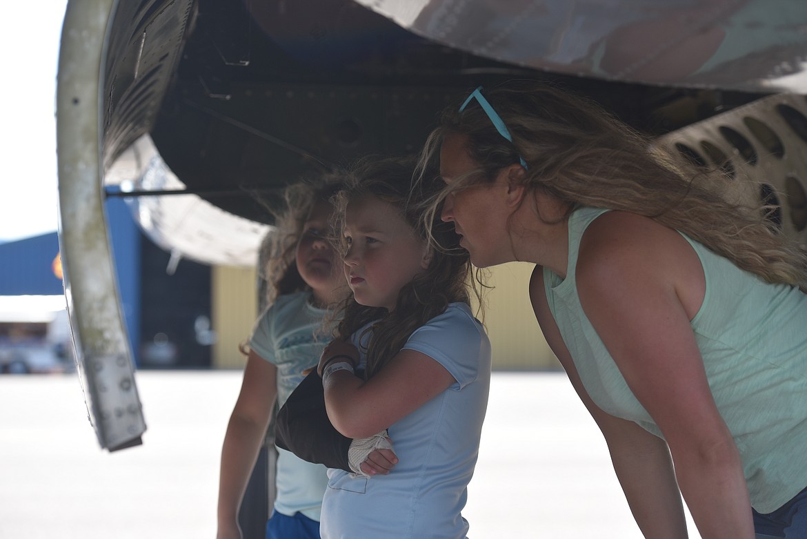 Kristie Birkenstock examines the signatures etched onto the B-25J Mitchell on display at Glacier Park International Airport with her twin 7-year-old daughters Lela and Linnea on Wednesday, July 6, 2022. (Derrick Perkins/Daily Inter lake)