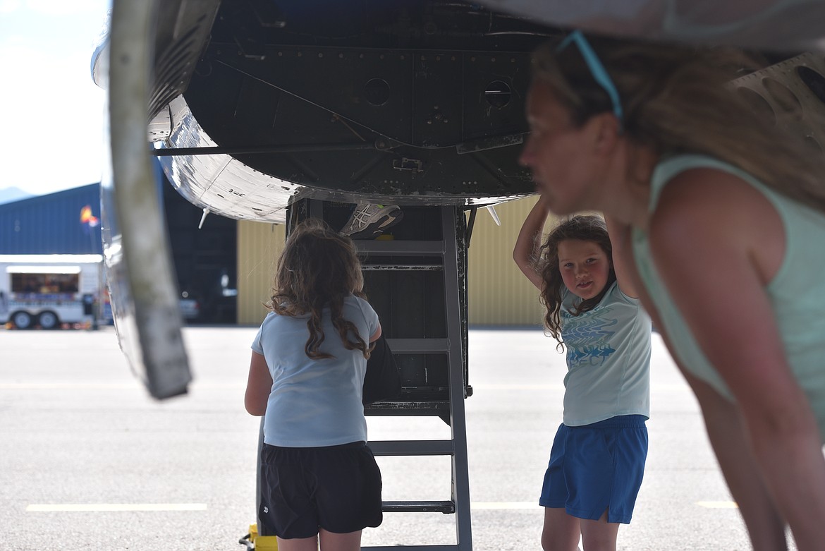 Kristie Birkenstock examines the signatures etched onto the B-25J Mitchell on display at Glacier Park International Airport while her twin 7-year-old daughters Lela and Linnea explore the plane on Wednesday, July 6, 2022. (Derrick Perkins/Daily Inter lake)