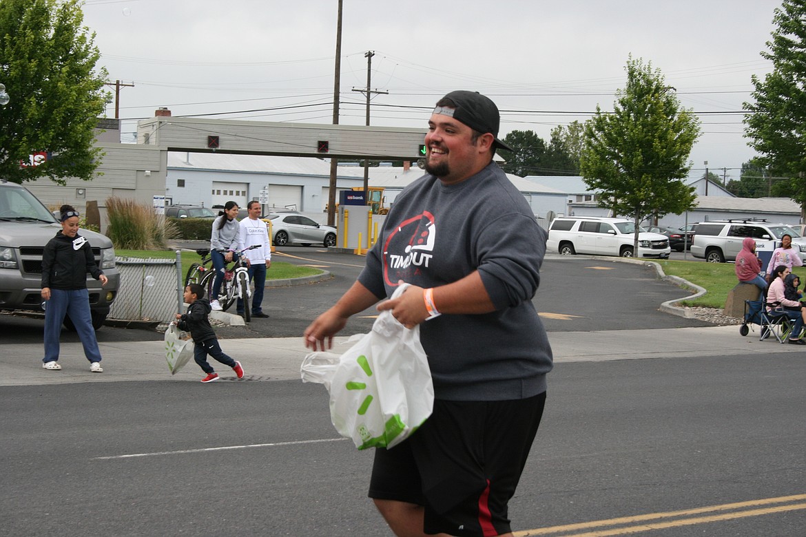 Timeout Pizza co-owner CJ Garza throws out candy during the July 4 parade in Othello.