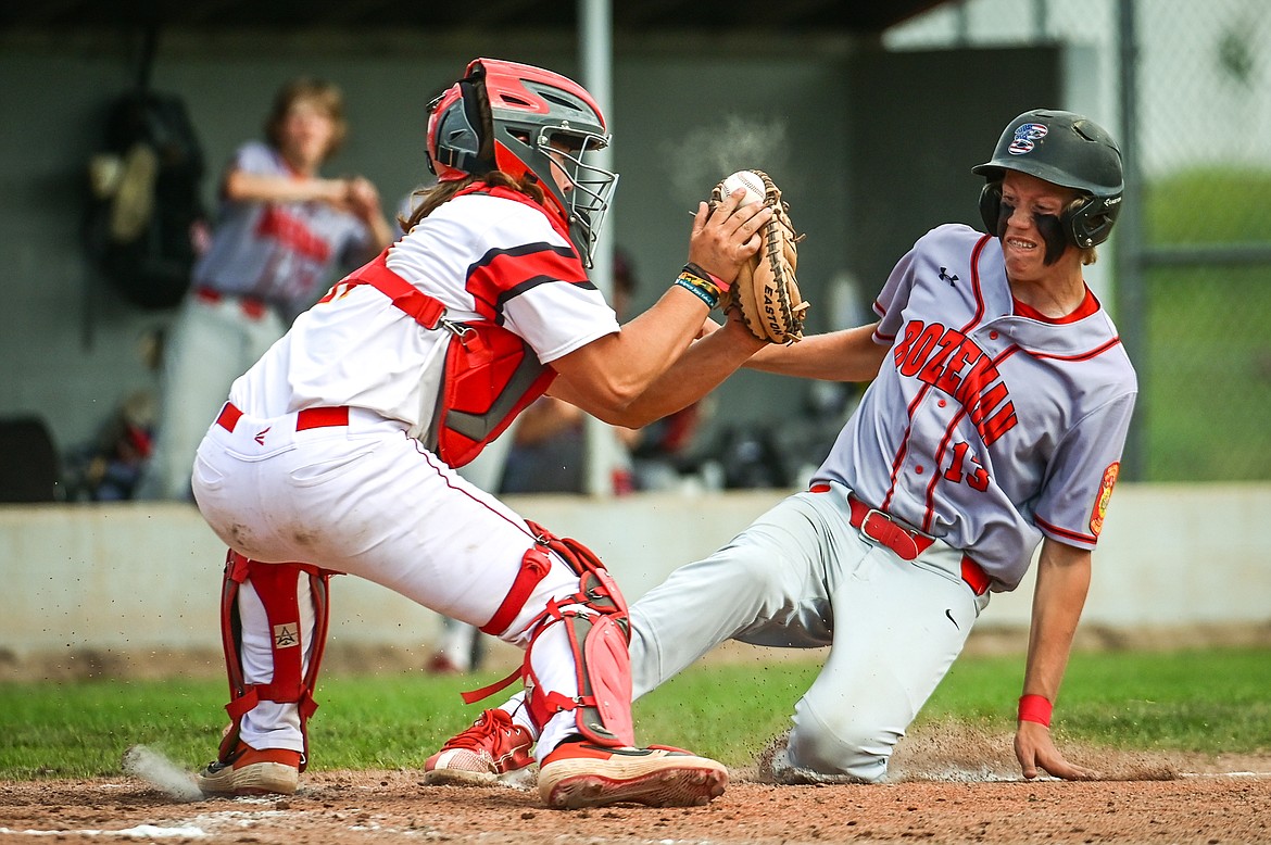 Bozeman's Torin Jeske (13) slides in safely on a play at the plate with Kalispell catcher TJ Hayek (21) in the John R. Harp Memorial Baseball Tournament at Griffin Field on Friday, July 8. (Casey Kreider/Daily Inter Lake)