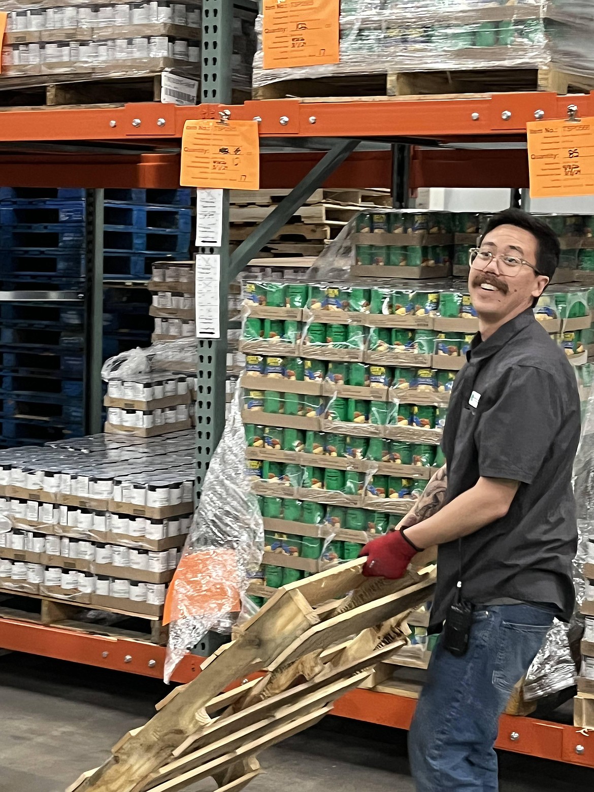 Supply chain associate Brandon Vasquez stocks the shelves of the emergency food assistance program at Second Harvest in Spokane on Friday morning.